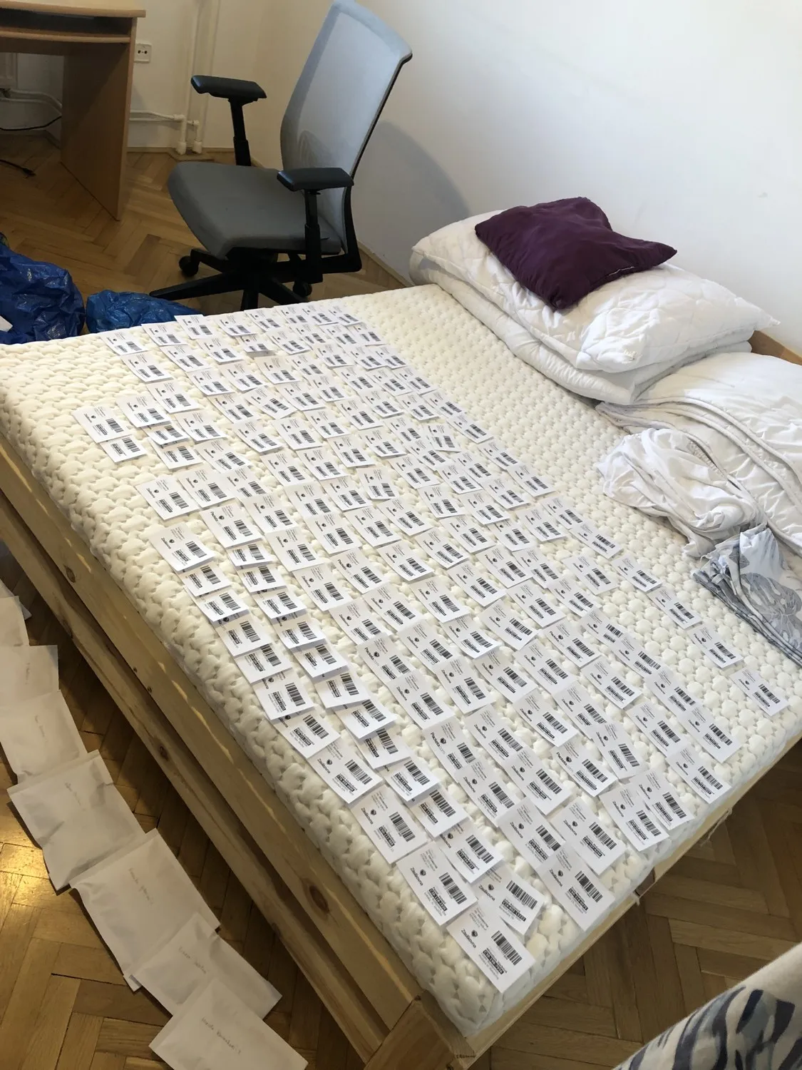 Posteľ v byte zavalená prepravnými štítkami a objednávkami